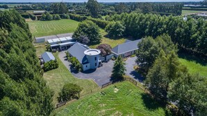 An aerial view of a property with a large circular building, multiple barns, and surrounding green fields.