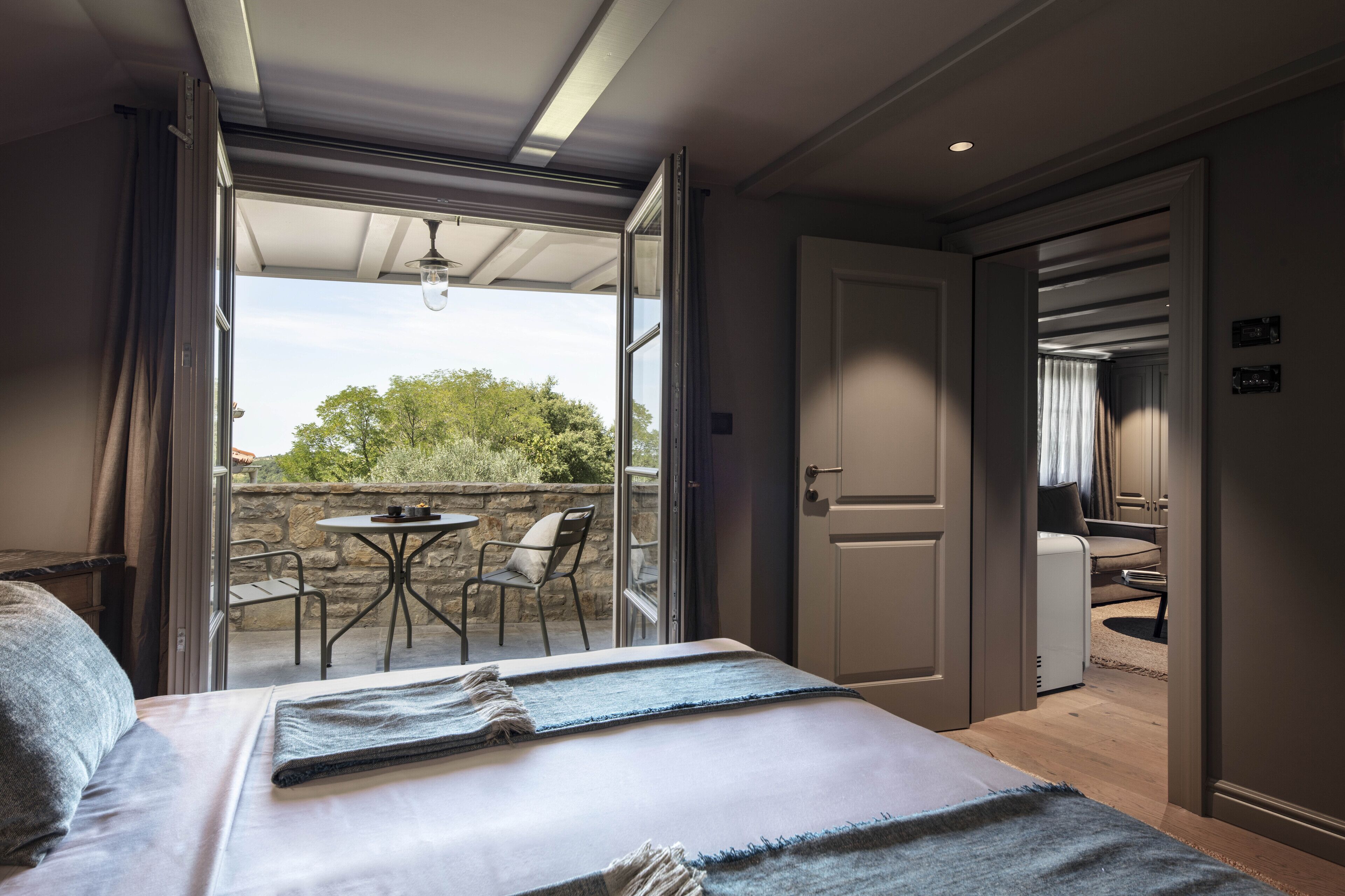 Un dormitorio con cama, ventana y balcón con mesa y sillas.