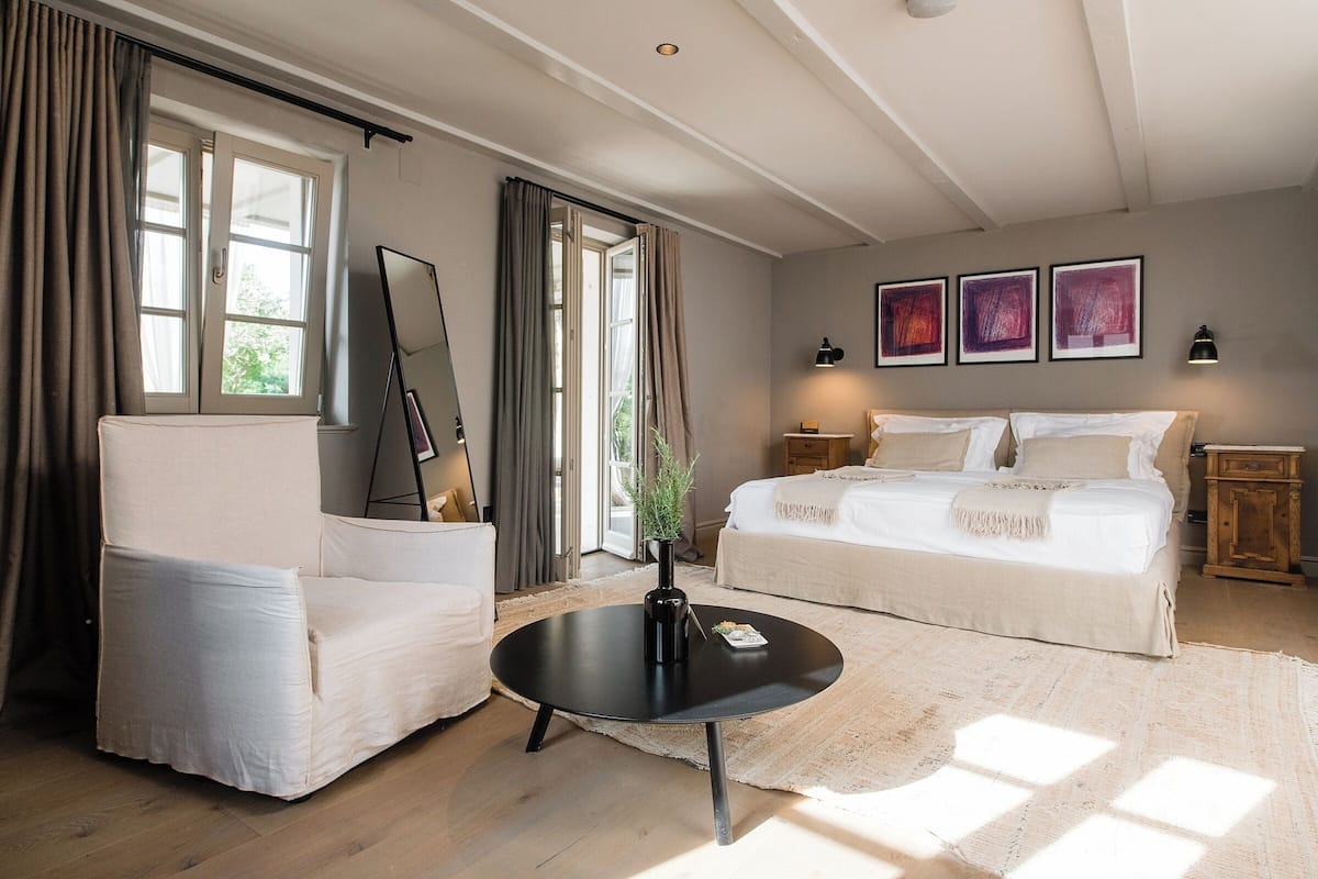 Une chambre à coucher avec un lit, une chaise, une table ronde et une fenêtre.