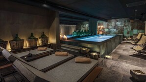 Un espace spa comprenant une grande baignoire, des tonneaux en bois et des sièges rembourrés.