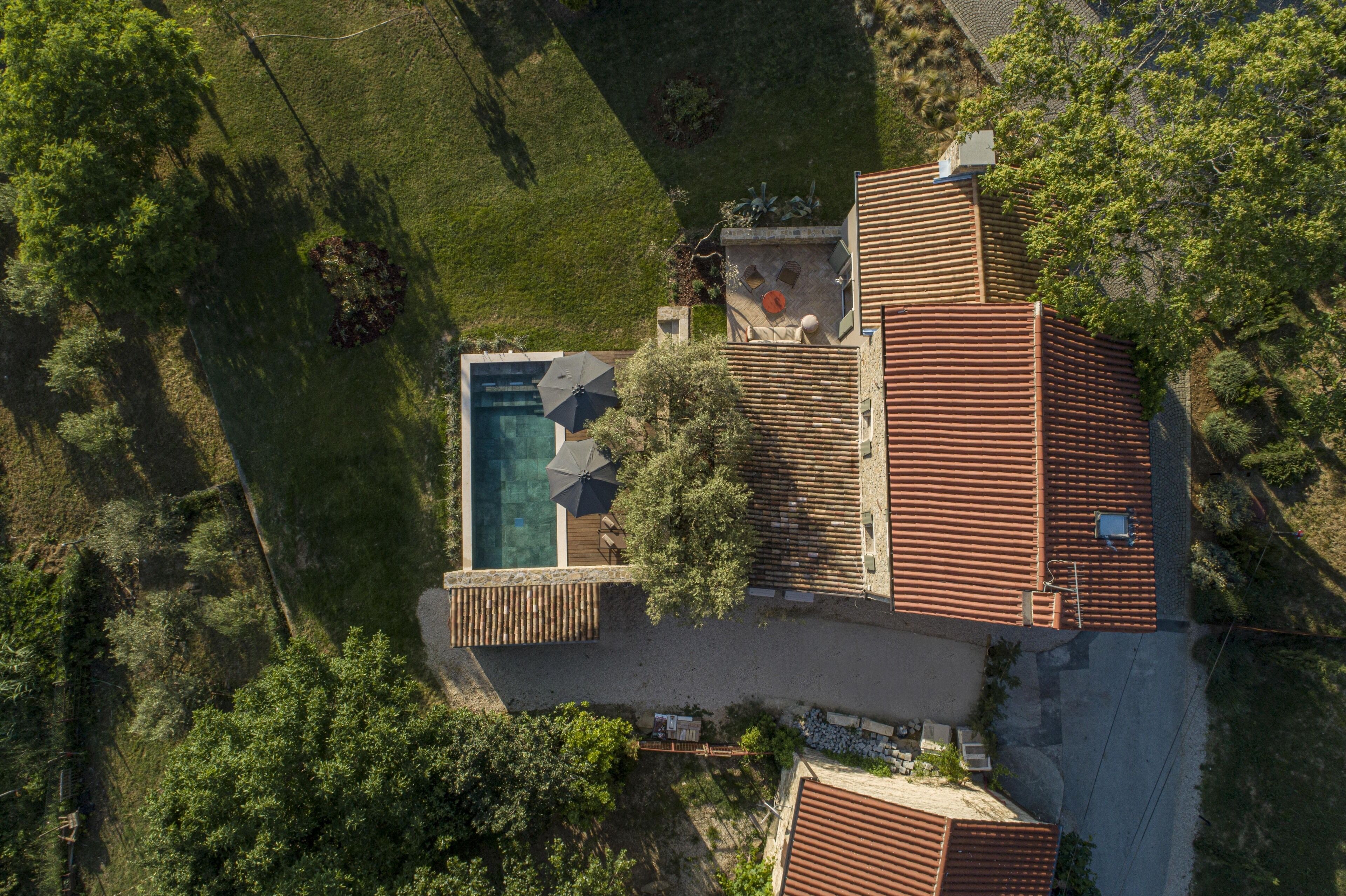 Vista aérea de una propiedad con piscina, un patio cubierto y un amplio jardín.