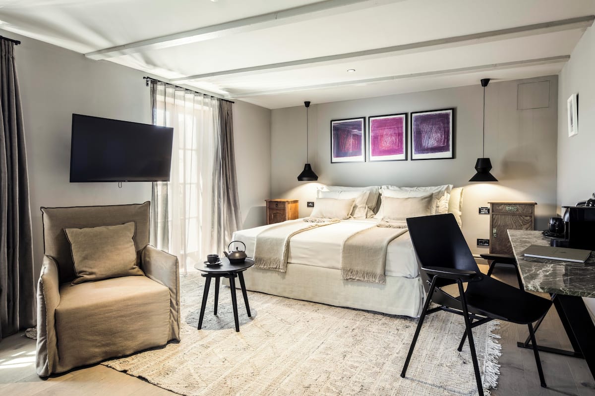 Une chambre d’hôtel moderne équipée d’un lit, d’une télévision, d’un bureau avec un ordinateur portable et d’une chaise.