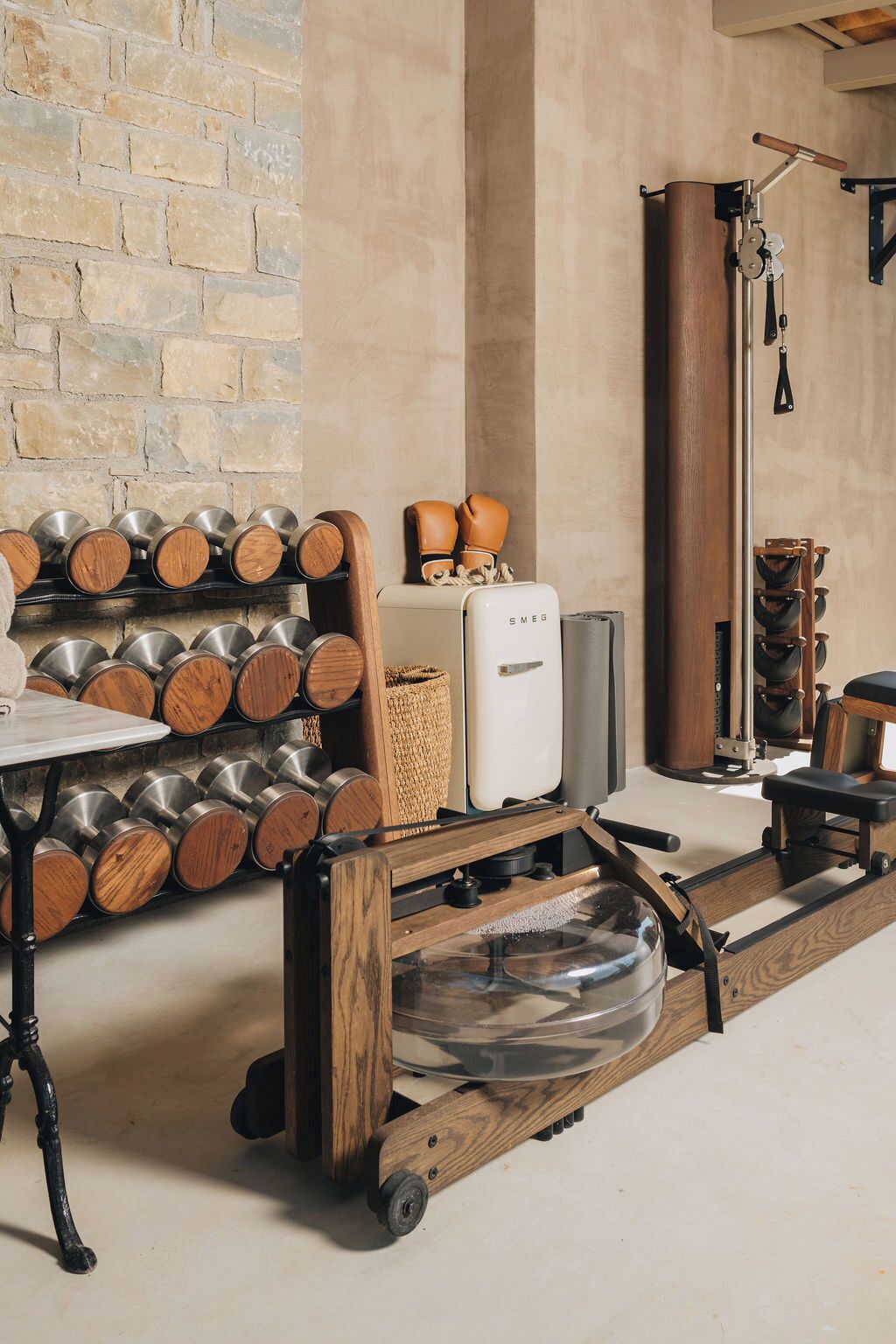 Une pièce avec un mur en briques, une table en bois avec des récipients en métal, un appareil électroménager blanc et un chariot en bois avec un récipient transparent.