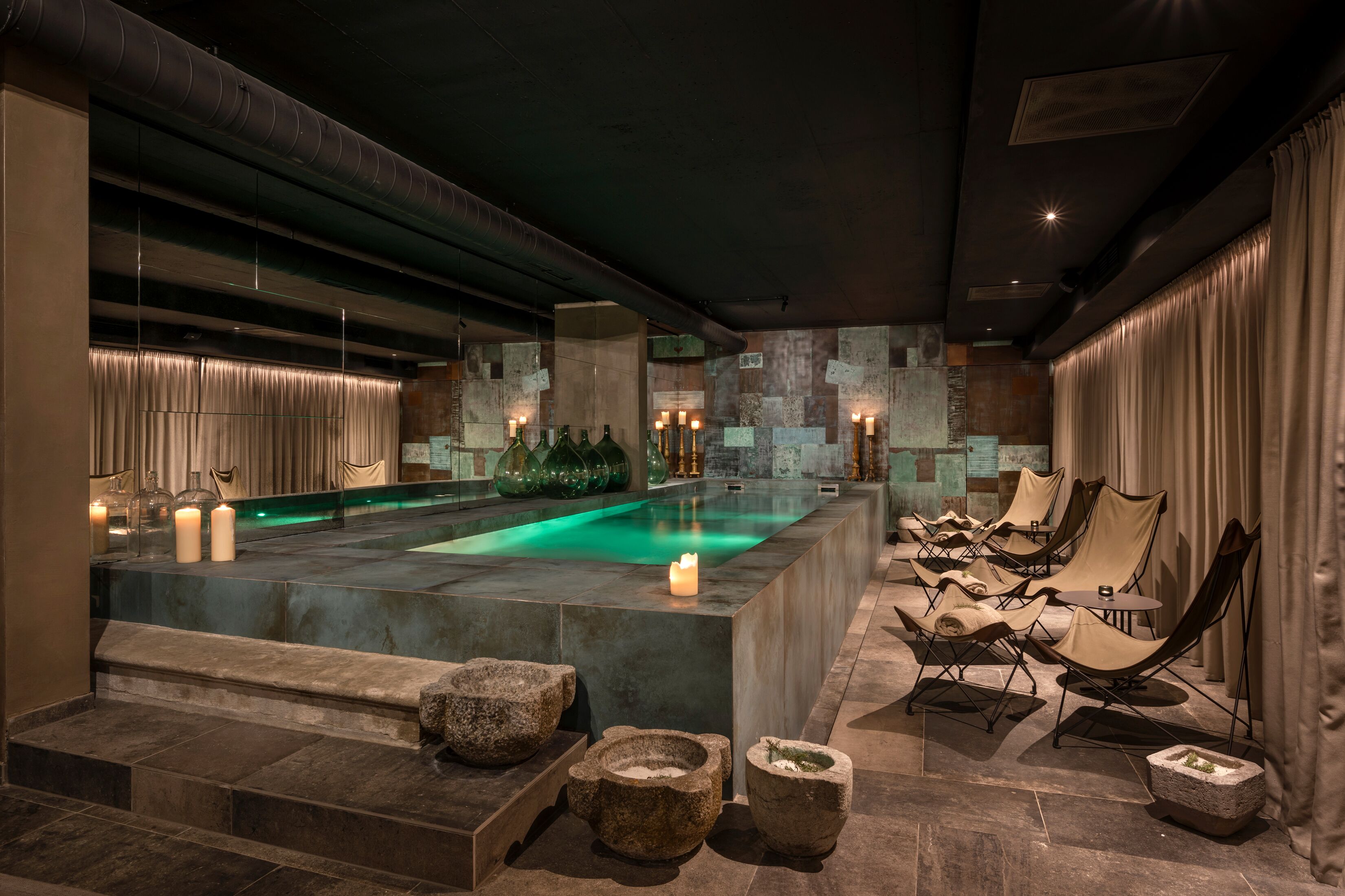 A spa area with a pool, stone seating, and candles.