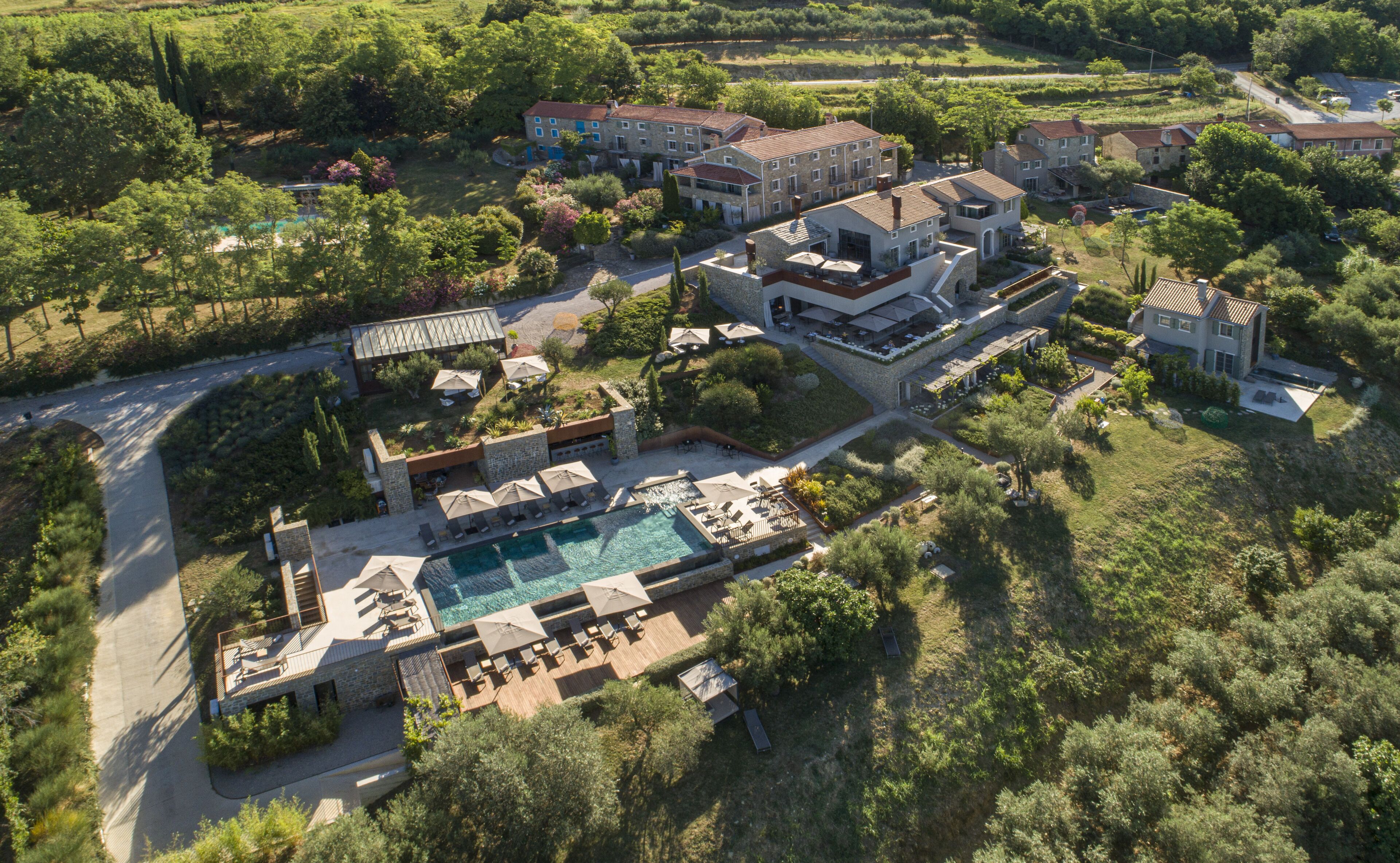 An aerial view of a resort with multiple buildings, a swimming pool, and lush greenery.