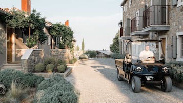 A cobblestone street with a parked vehicle and a building with stone walls and a balcony.