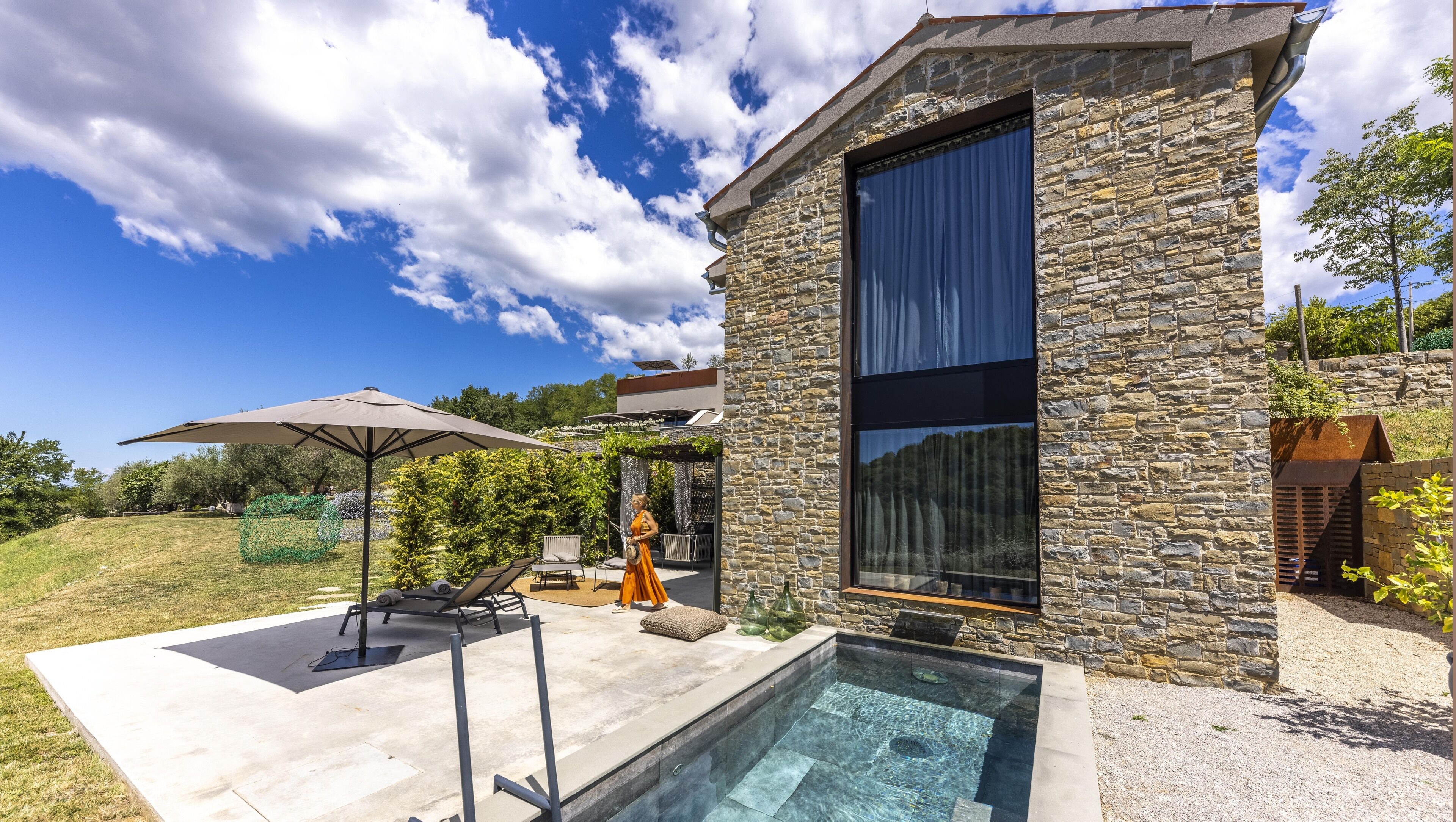 A modern house with a stone exterior, a large window, and a swimming pool.