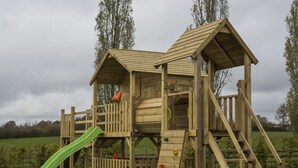 Una estructura de juego de madera con un tobogán y elementos para trepar.