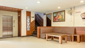 A reception area with a wooden bench, a small table, a staircase, and a painting on the wall. - Treebo Red Petal Jalandhar (Jalandhar)