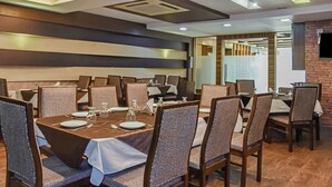 A dining area with tables set for four, each with chairs, plates, cutlery, and glasses. - Treebo Red Petal Jalandhar (Jalandhar)