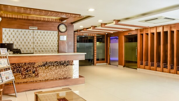 A reception area with a wooden reception desk, a clock, and a glass door leading to a hallway. - Treebo Red Petal Jalandhar (Jalandhar)