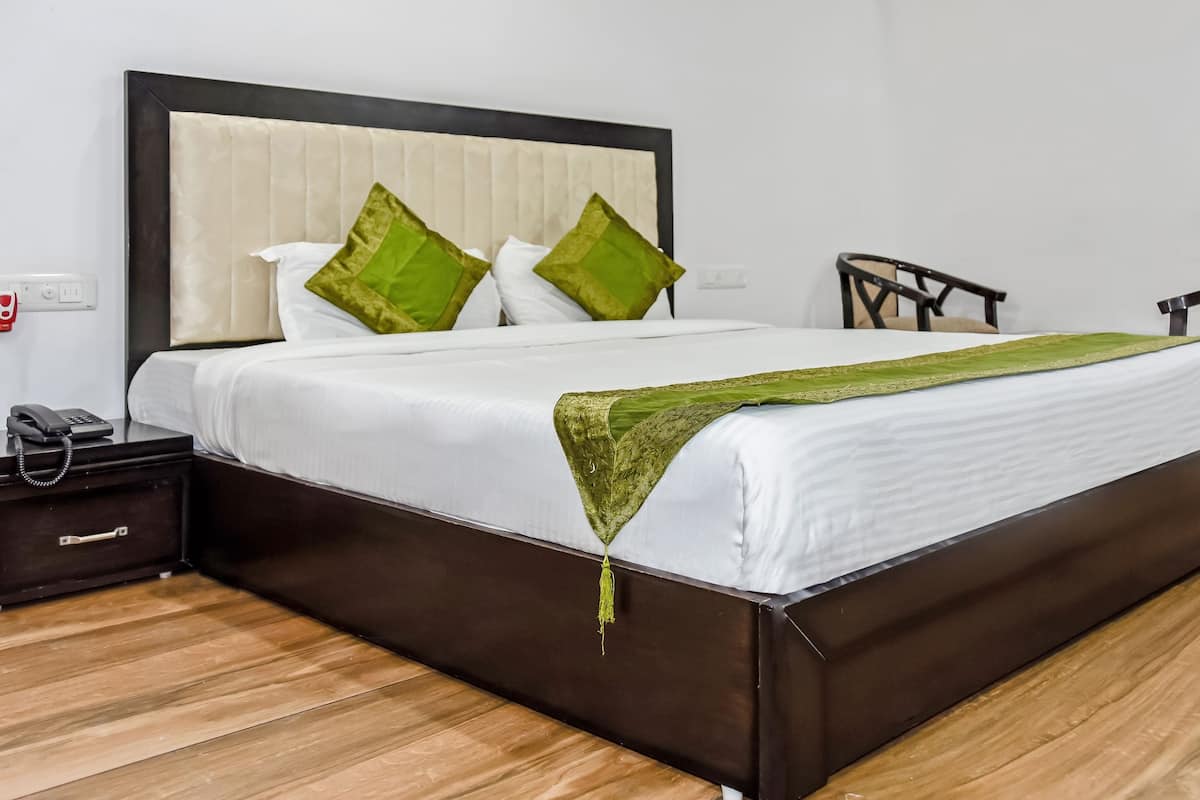 A hotel room with a large bed, a bedside table with a phone, and a nightstand.