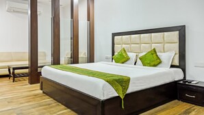 A neatly made bed with a white and green bedspread, two green pillows, and a dark wooden headboard. - Treebo Red Petal Jalandhar (Jalandhar)