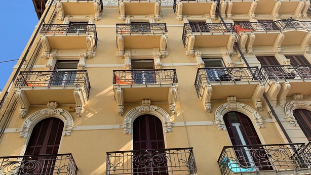 Un edificio de varios pisos con balcones ornamentados y ventanas de arco.