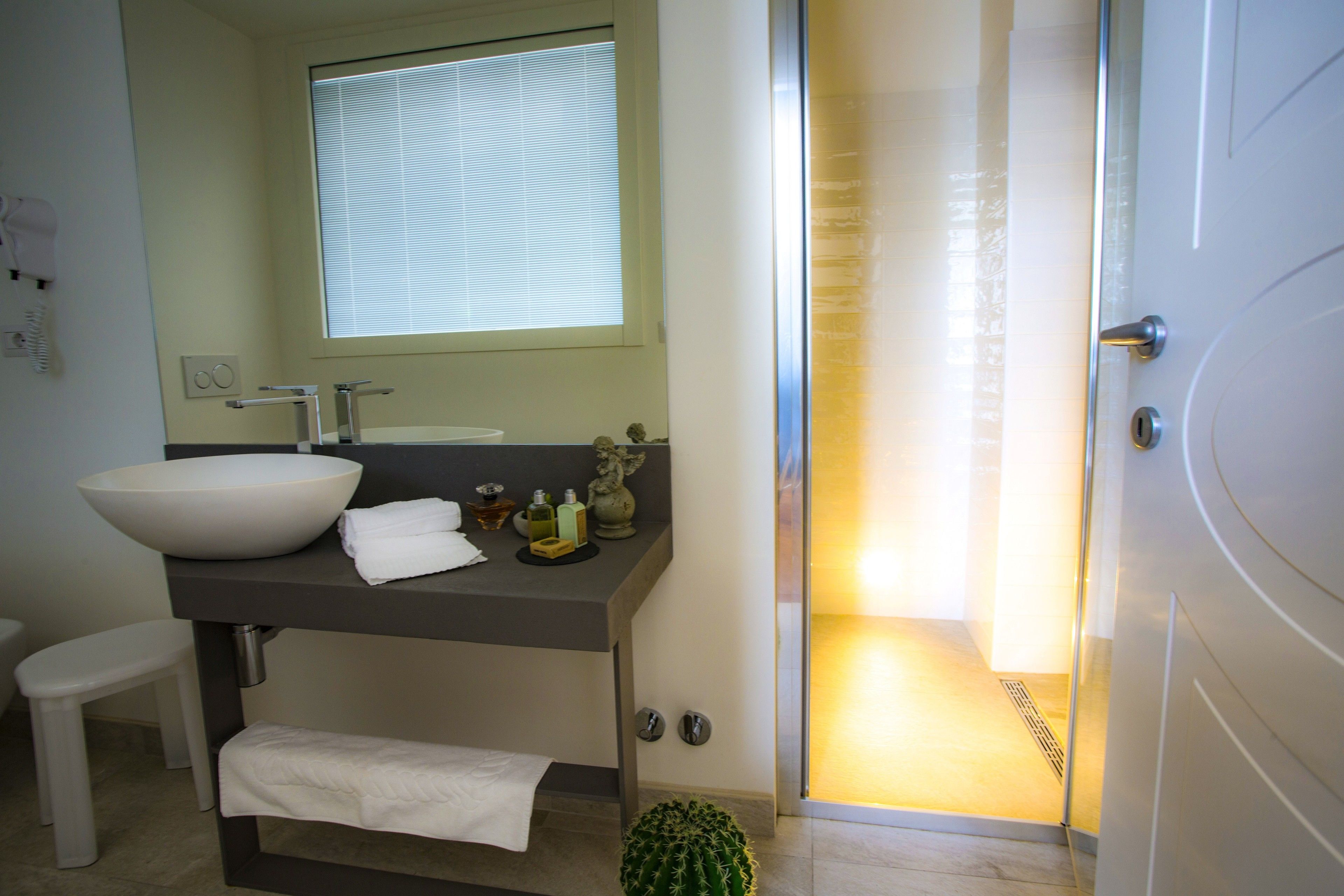 Une salle de bain moderne avec un grand lavabo blanc, un miroir et un espace douche.