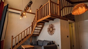 Een gezellige woonkamer met een houten trap, een bank, een klein tafeltje en een hanglamp.