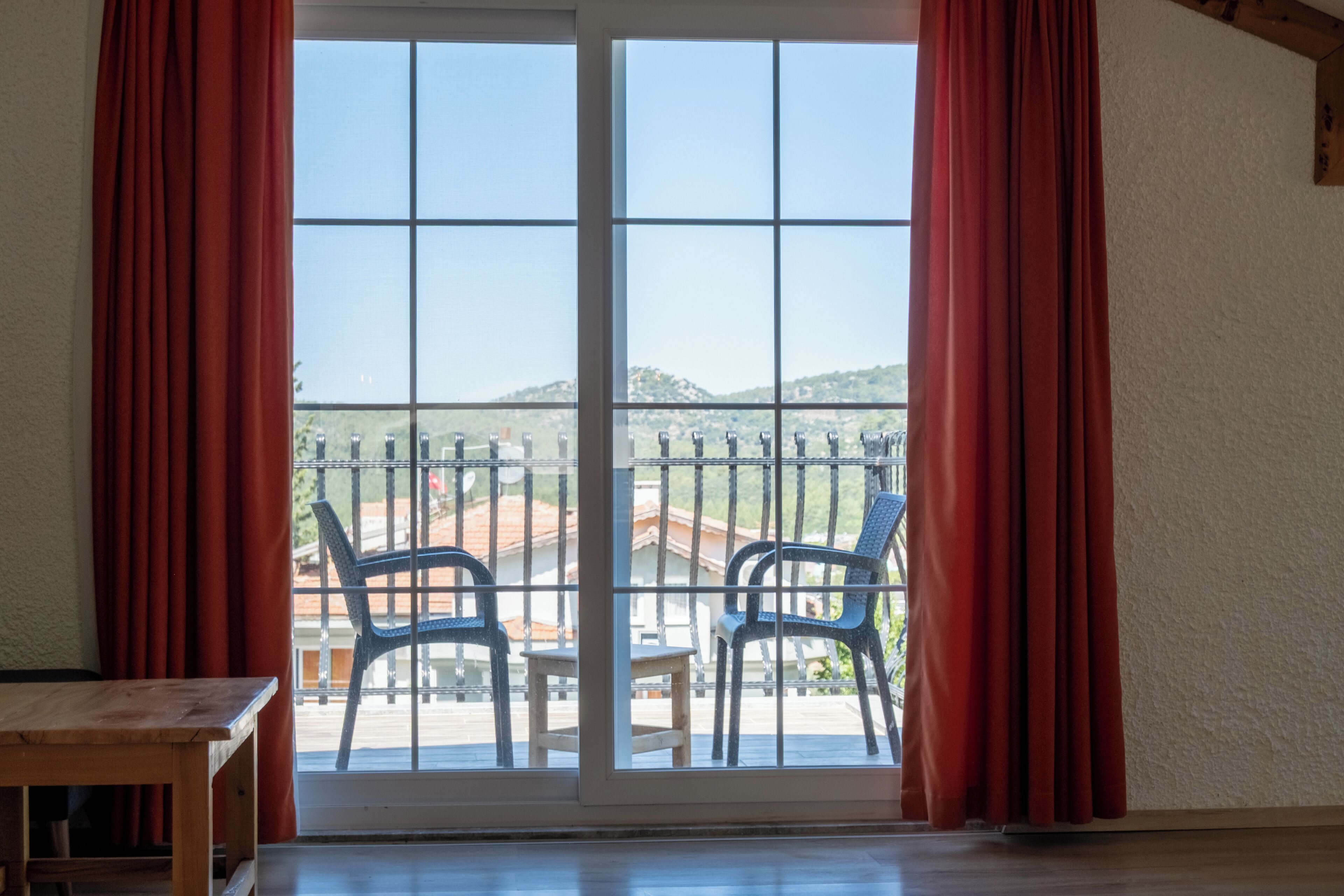 A room with a sliding glass door leading to a balcony with two chairs and a small table.