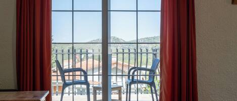 A room with a sliding glass door leading to a balcony with two chairs and a small table.