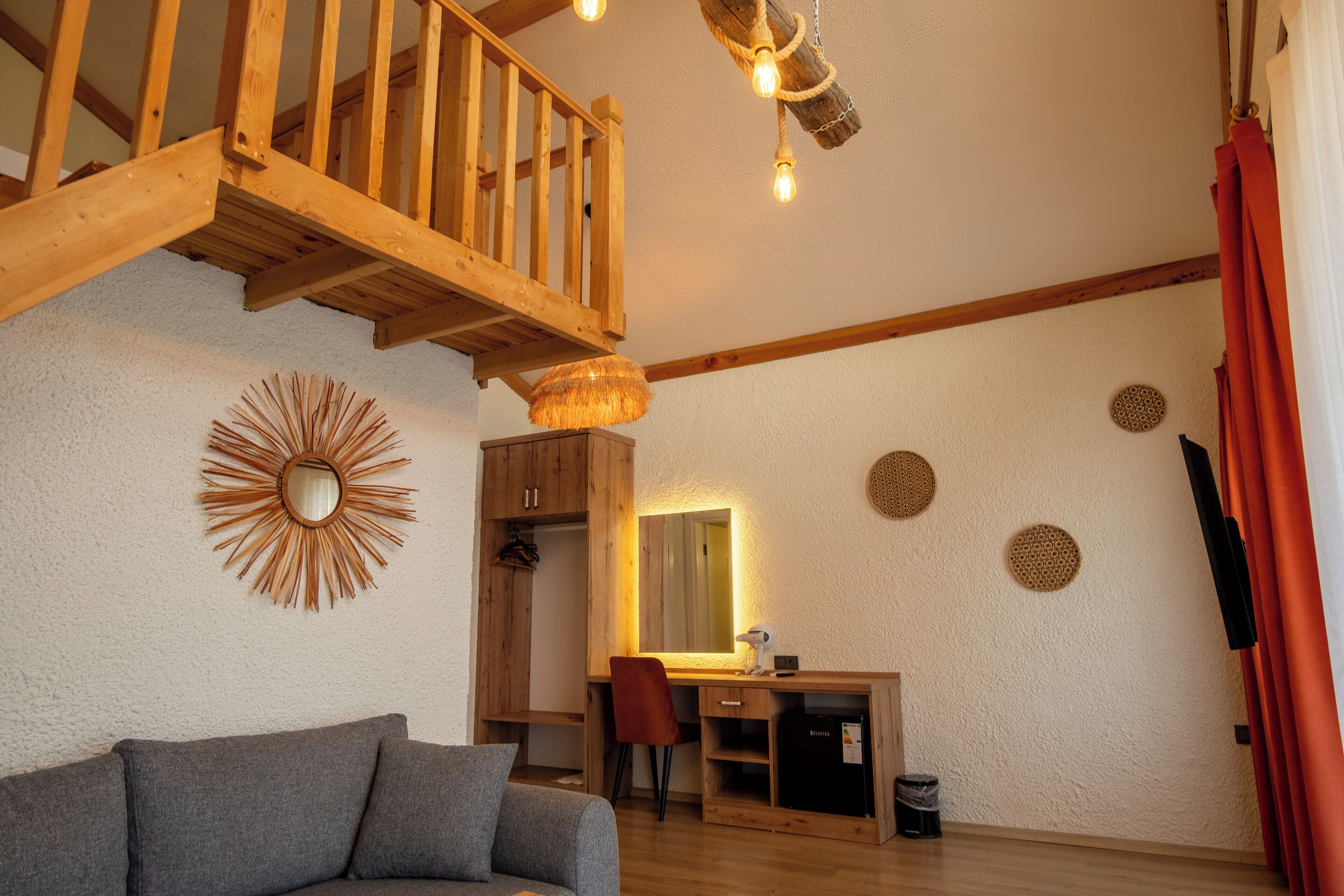 Een ruime woonkamer met een houten trap, een bureau met spiegel en een moderne kroonluchter.