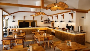Een restaurant met houten meubels, een bar en hangende lampen.
