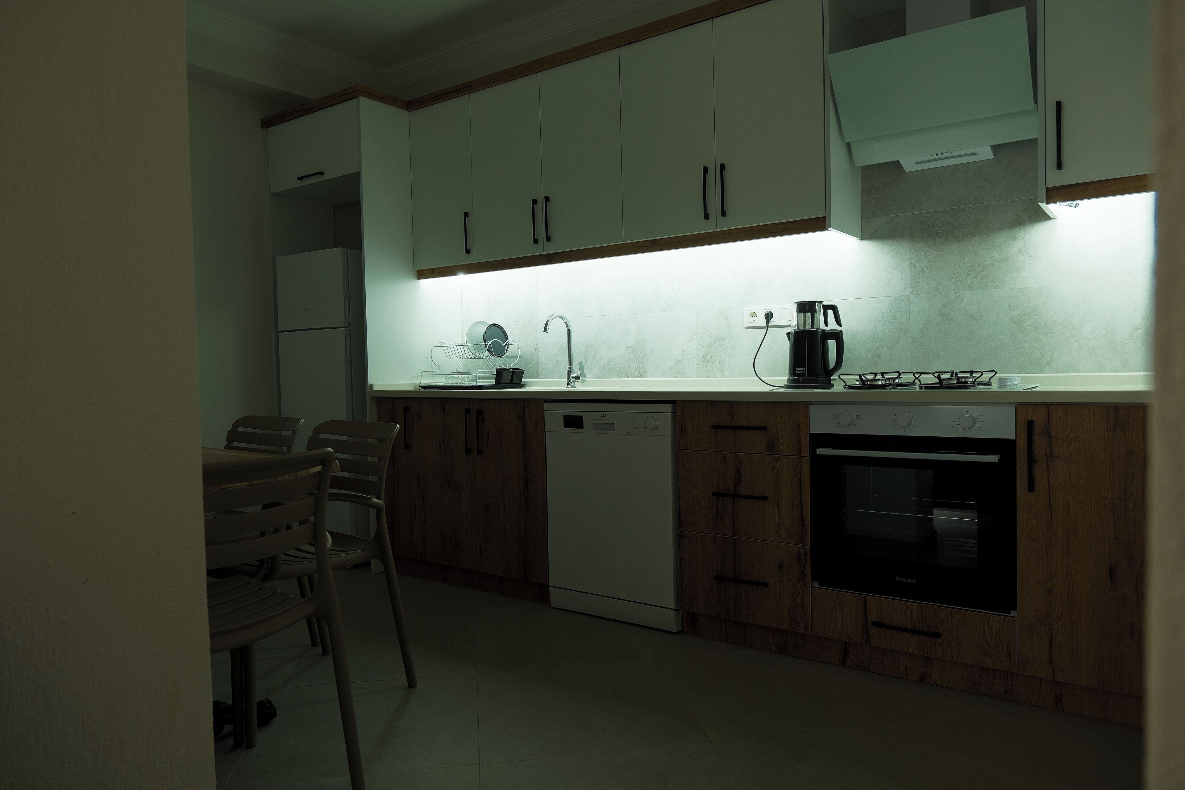 A compact kitchen with white cabinets, a dishwasher, a stove, and a sink.