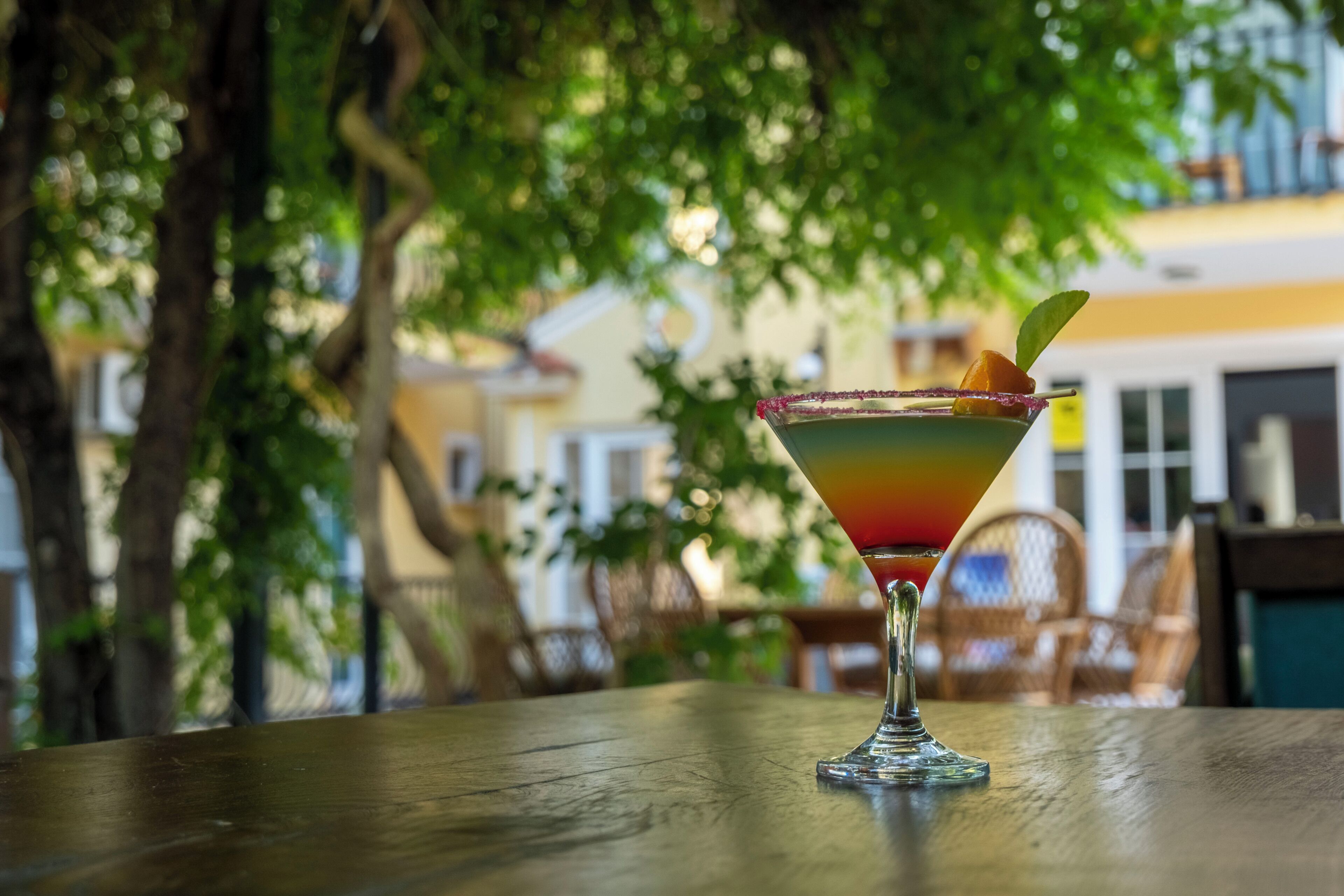 A cocktail on a table with a blurred outdoor background.