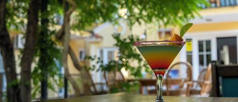 A cocktail on a table with a blurred outdoor background.