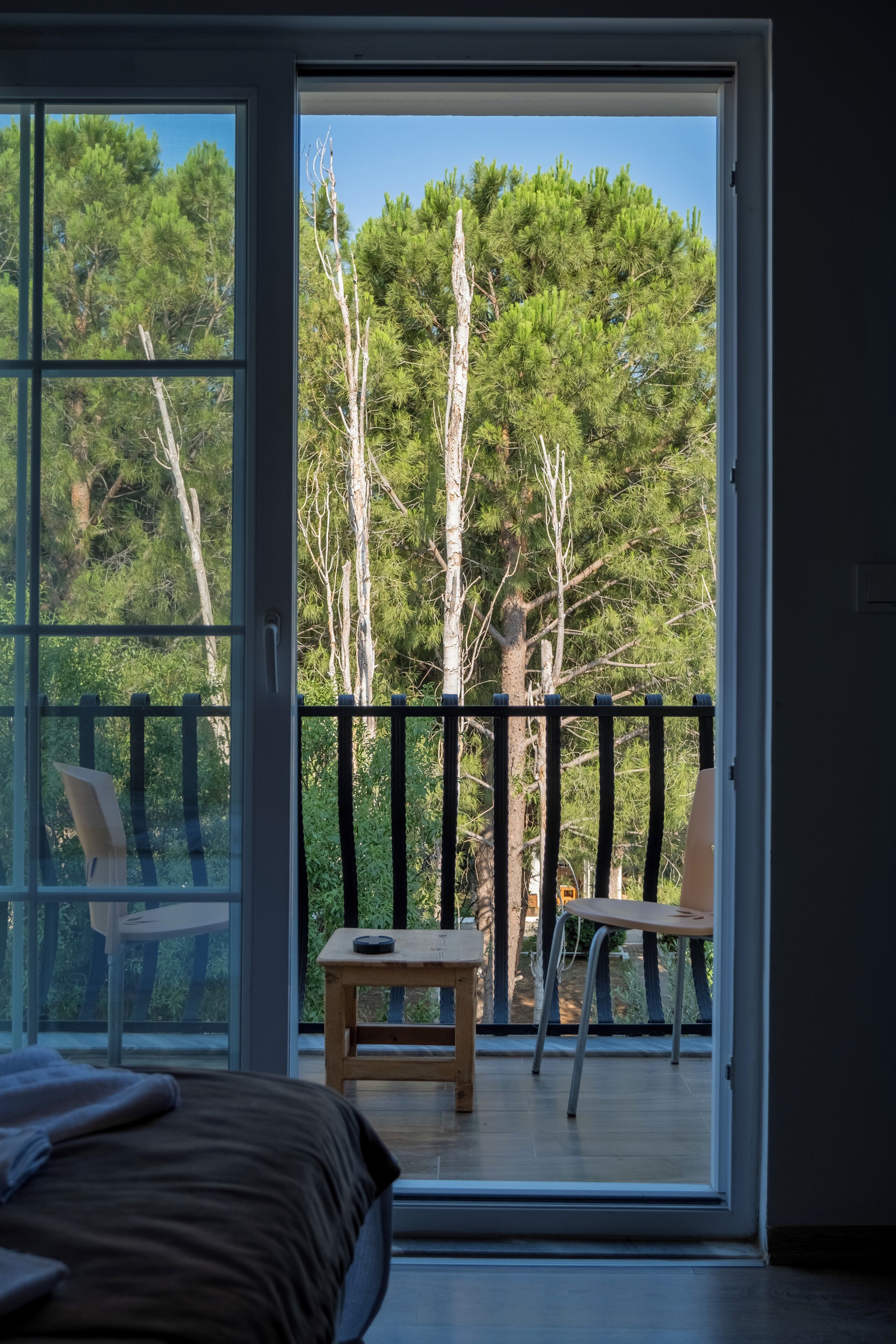 A bedroom with a large sliding glass door leading to an outdoor balcony with a wooden table and chairs.