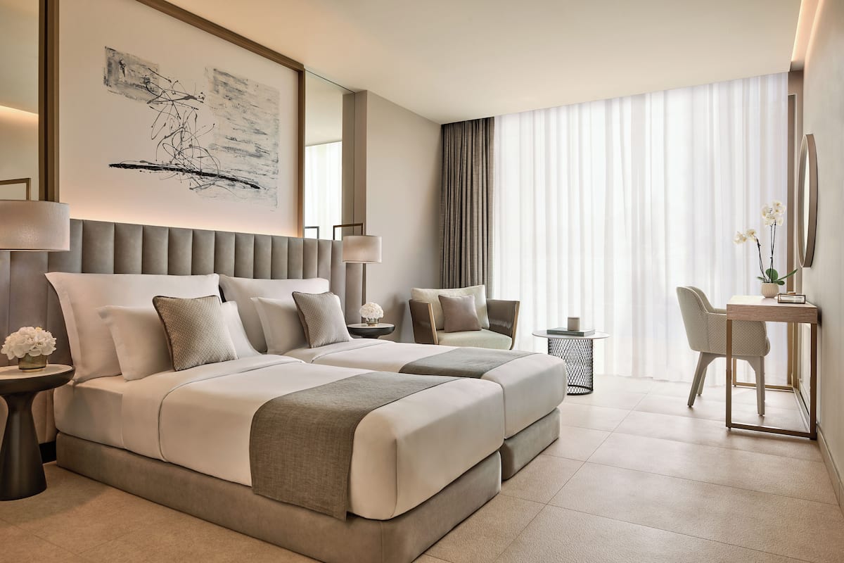 A modern hotel room with a large bed, a desk, and a chair.