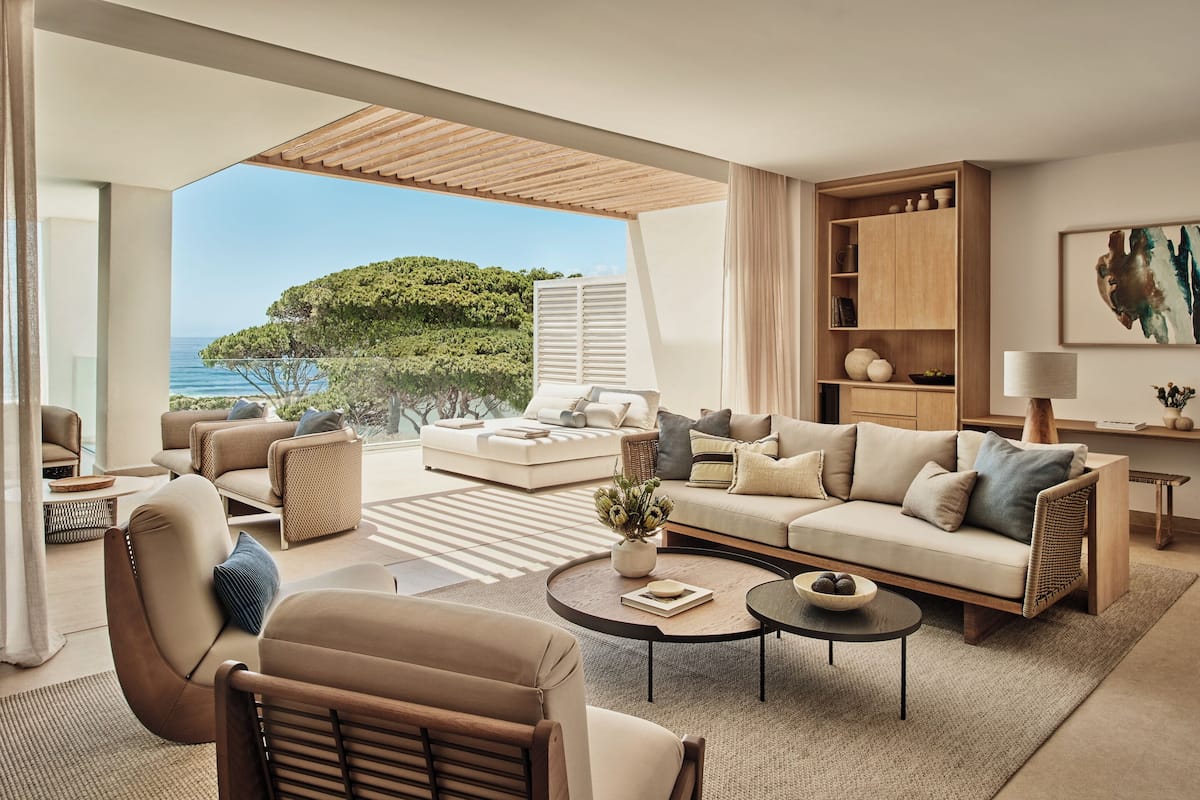 A modern living room with a sofa, armchairs, a coffee table, and a view of the sea.