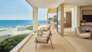A modern interior with a view of the sea, featuring a balcony with seating and a dining area.