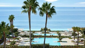 A resort with a large pool, palm trees, and a view of the ocean.
