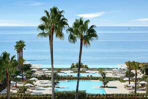 A resort with a large pool, palm trees, and a view of the ocean.