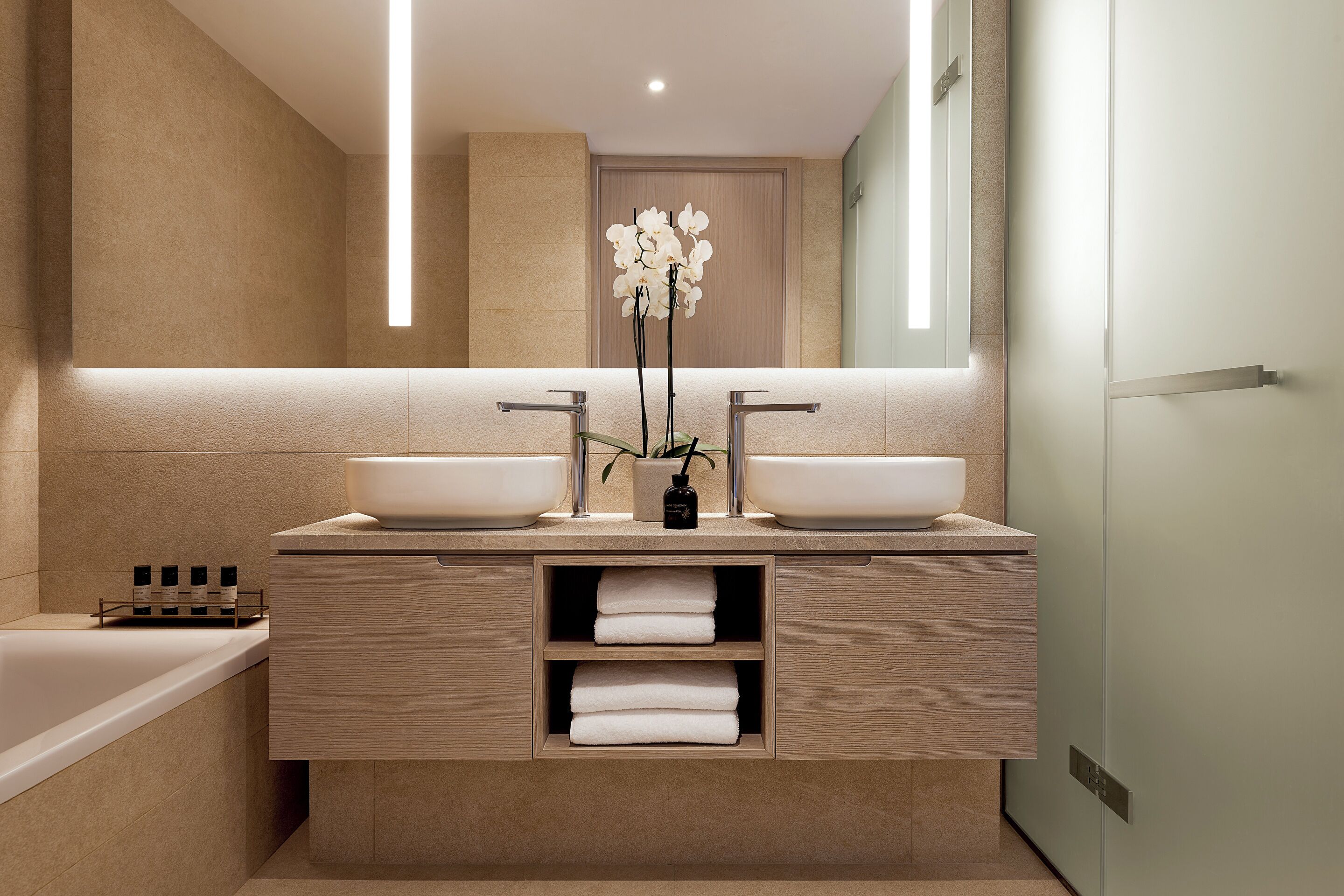 Un baño moderno con dos lavamanos, una bañera y un espejo.