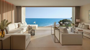 A modern living room with a view of the ocean, featuring a sofa, coffee table, and a dining area. - Ikos Andalusia - All Inclusive (Estepona)