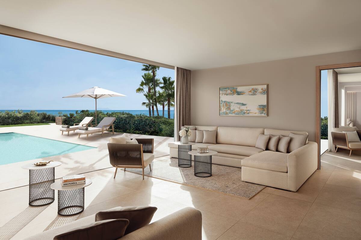 A modern living room with a pool, a sofa, and a view of the ocean.