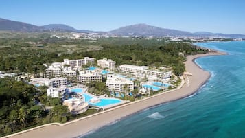 Un resort con varias edificaciones, una playa y un área de piscina.