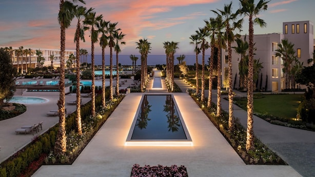 A resort with a pool, palm trees, and a sunset view.