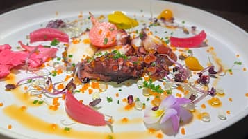 A white plate with a variety of food items including octopus, vegetables, and caviar.