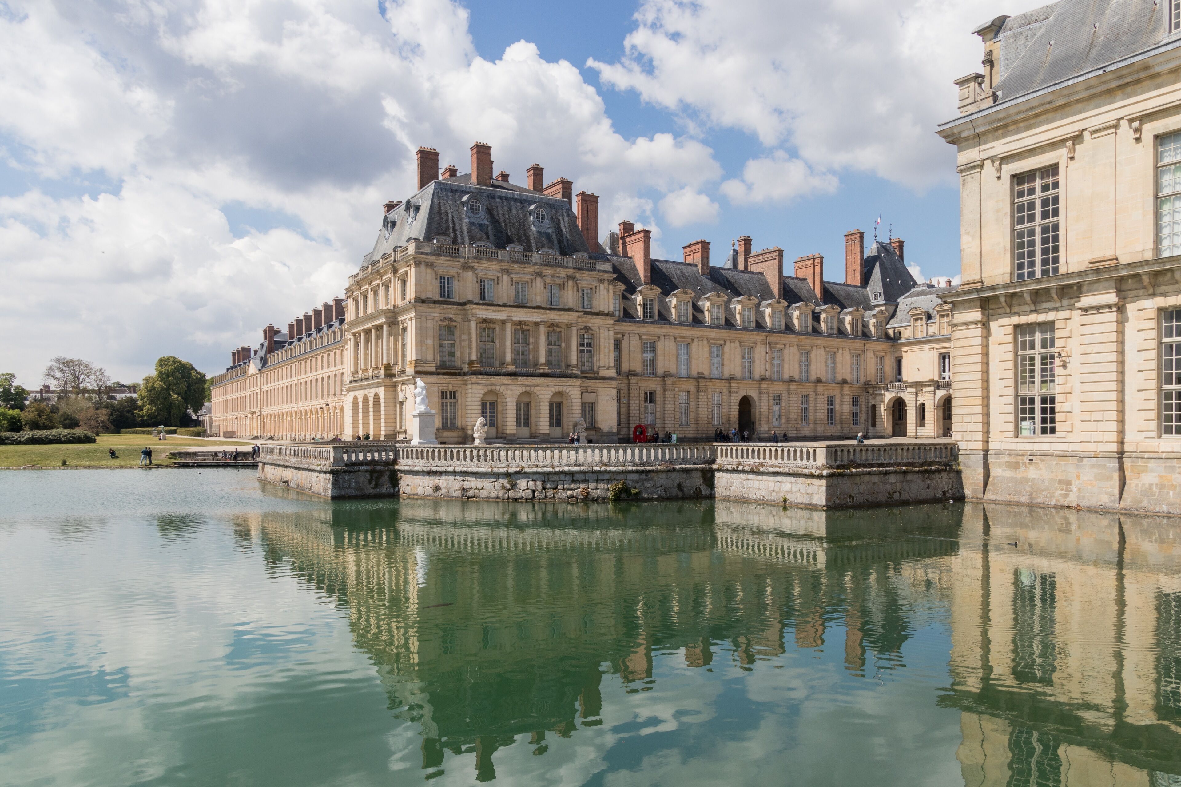 A historic building with classical architecture, a large courtyard, and a reflective water body.