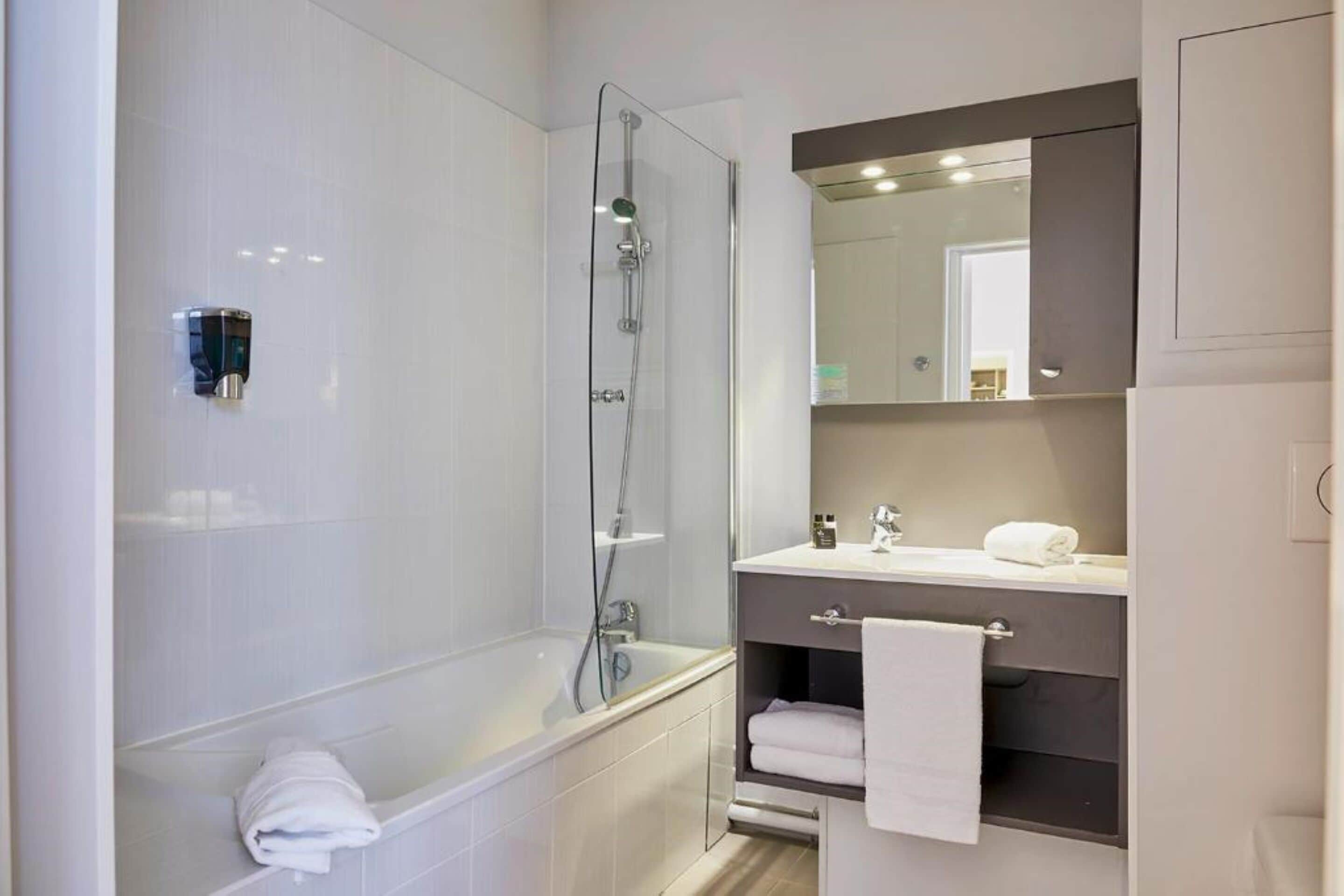 Une salle de bain moderne dotée d’une douche à parois de verre, d’une baignoire sur pieds et d’un meuble-lavabo avec un miroir.