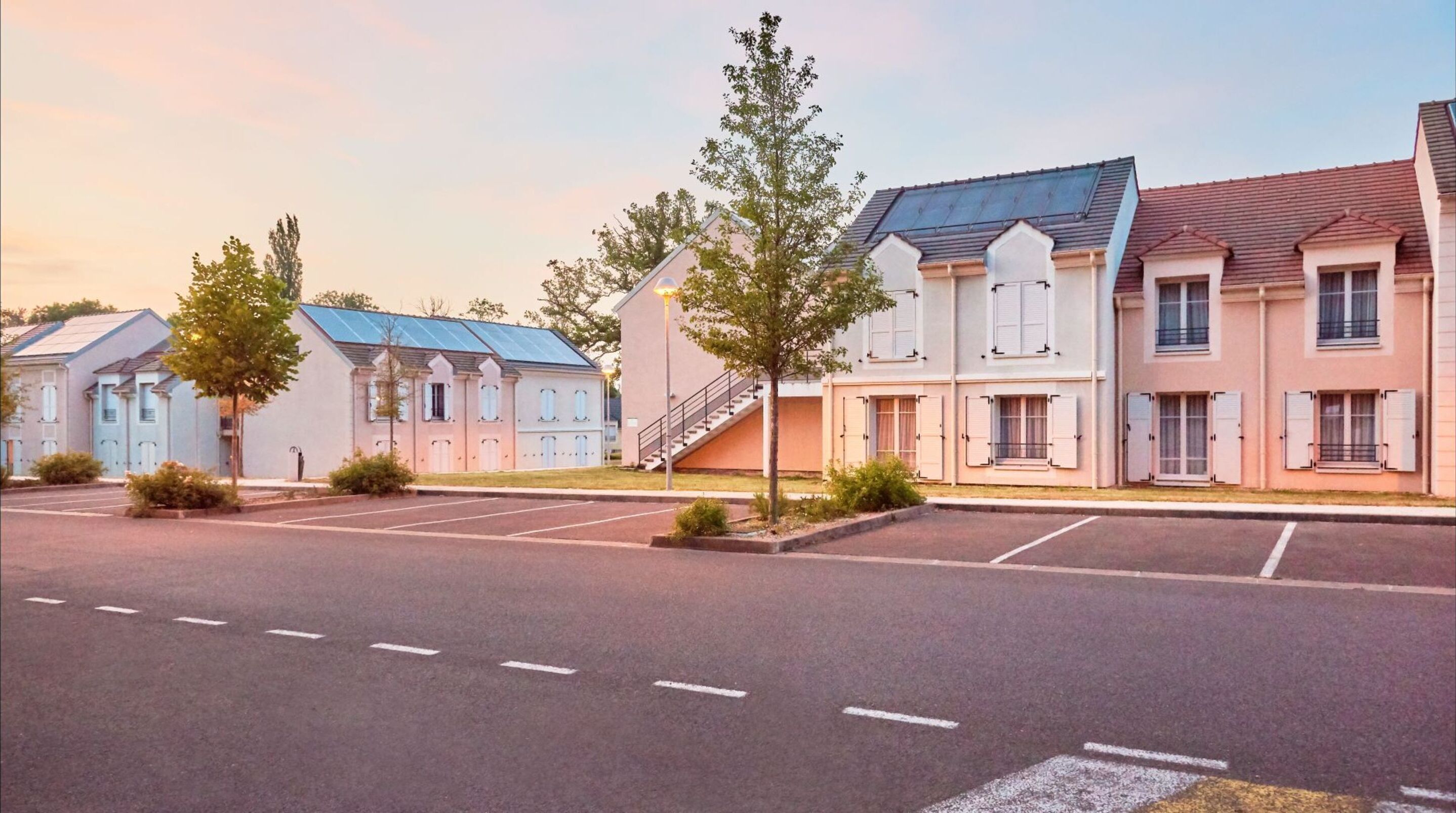 A row of modern, two-story buildings with a flat roof and a parking lot in front.