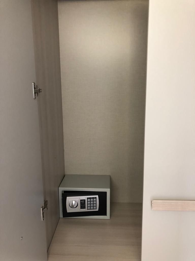 A small, enclosed space with a metallic safe and a door.