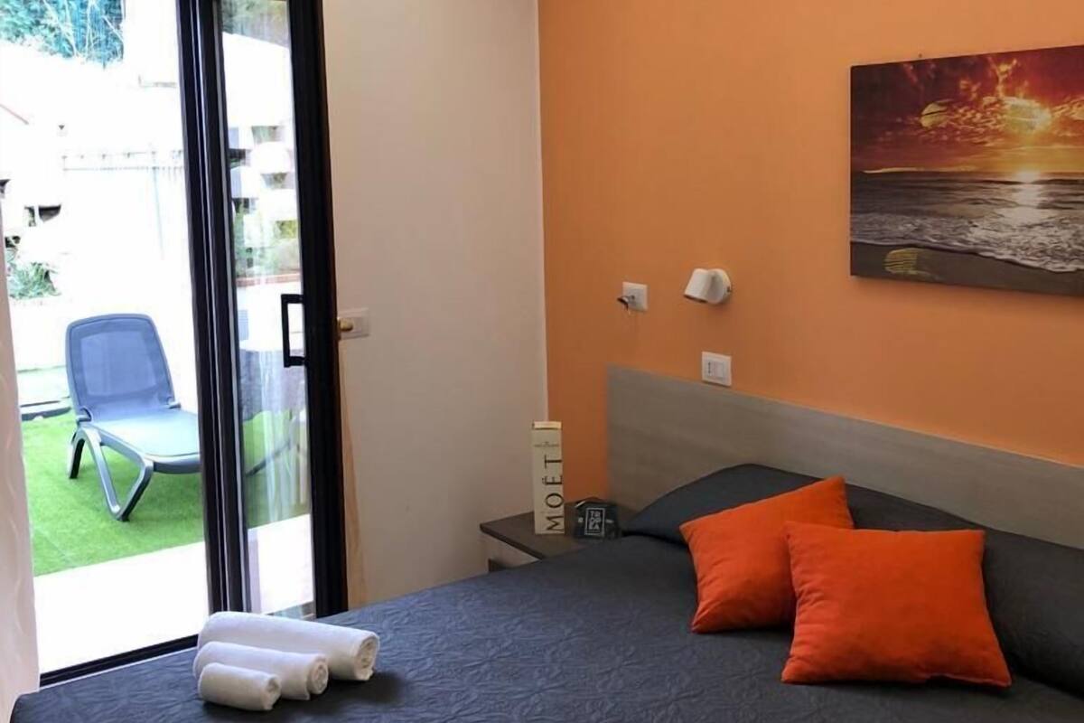 A hotel room with a bed, a painting on the wall, and a view of the outside.