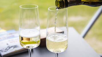 Dos copas de vino sobre una mesa, con una botella siendo vertida en una de ellas.