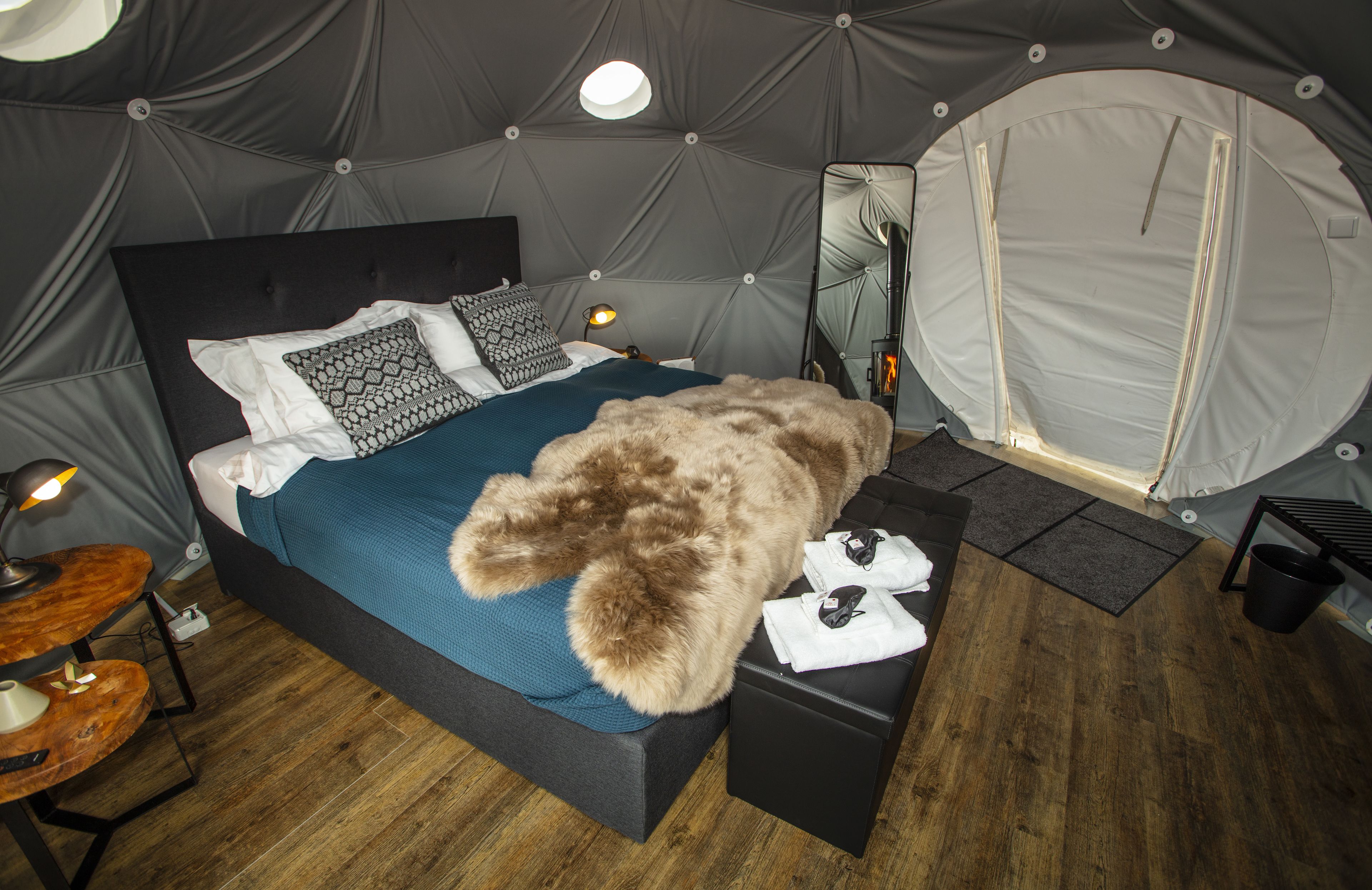 A tented room with a bed, a table, and a mirror.