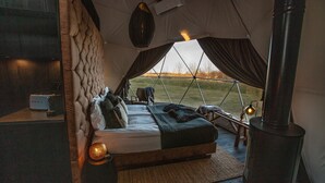A cozy tented accommodation with a bed, a heater, and a view of the outdoors. - Reykjavik Domes (Reykjavik)