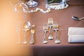 Une table dressée avec des couverts en argent et un verre à vin, ce qui indique un repas formel.