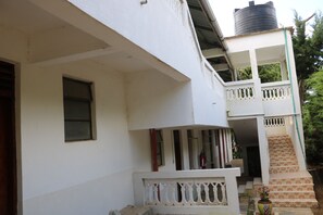 A two-story building with a balcony on the upper floor, a water tank on the roof, and a staircase leading to the upper level. - Taita Rocks Hotel (Taita Hills)