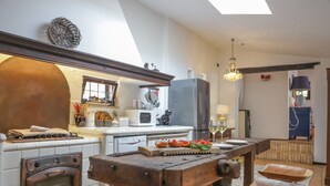 Een keuken met een fornuis, oven en een houten tafel met stoelen.